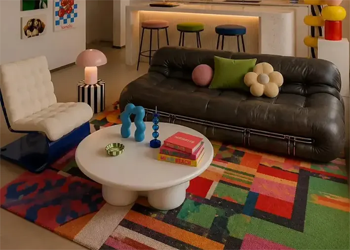 Salotto in stile Memphis con tappeto multicolore e arredi colorati: come abbinare i colori del terrazzo a mobili e tessuti