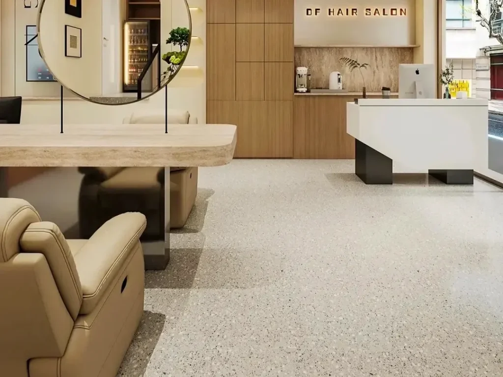 Pavimento in terrazzo Base Grigio Chiaro con Aggregati Bianchi Fini, salone parrucchiere moderno in stile minimalista con poltrone in pelle beige e specchi rotondi a pavimento.