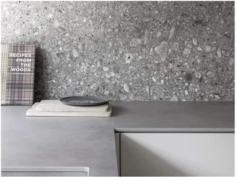 Piastrelle terrazzo inorganico per rivestimento parete cucina, finitura grigia con aggregati di pietra, abbinato a piano di lavoro minimalista